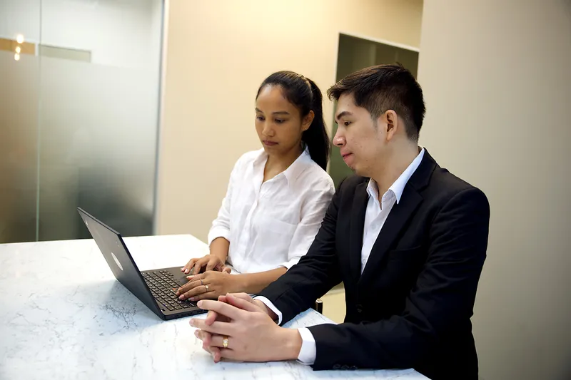 Two YPN Accounting team members working on a laptop at a marble counter