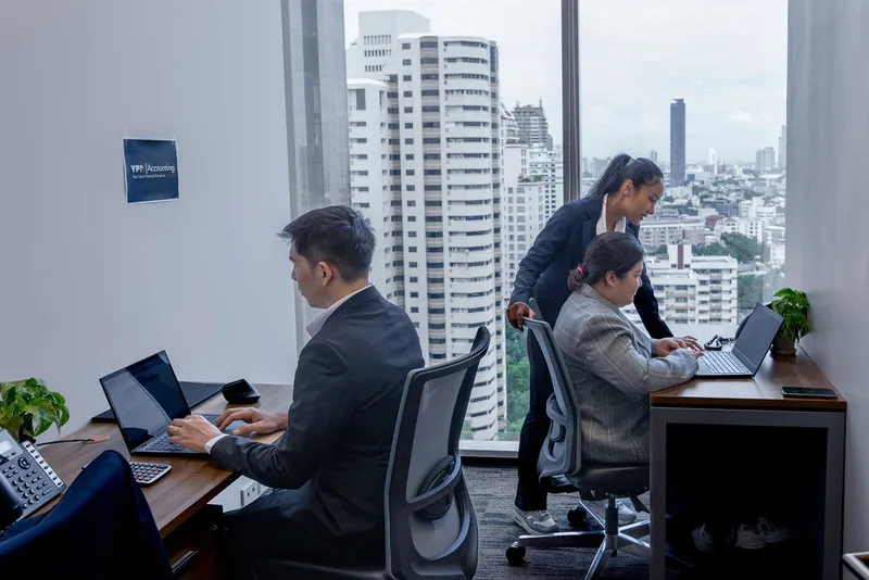 YPN Accounting team members at their desks by a window over Bangkok