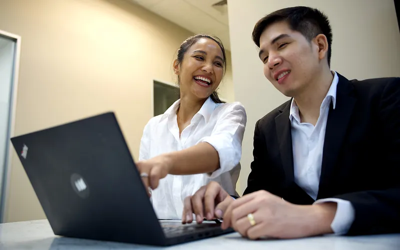 A YPN Accounting team member laughing with a colleague while pointing at a laptop