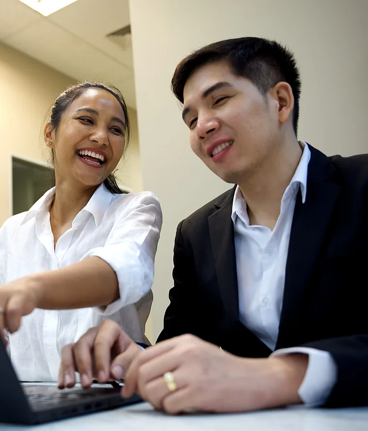 Yupin Numyen laughing with a colleague while working at a laptop